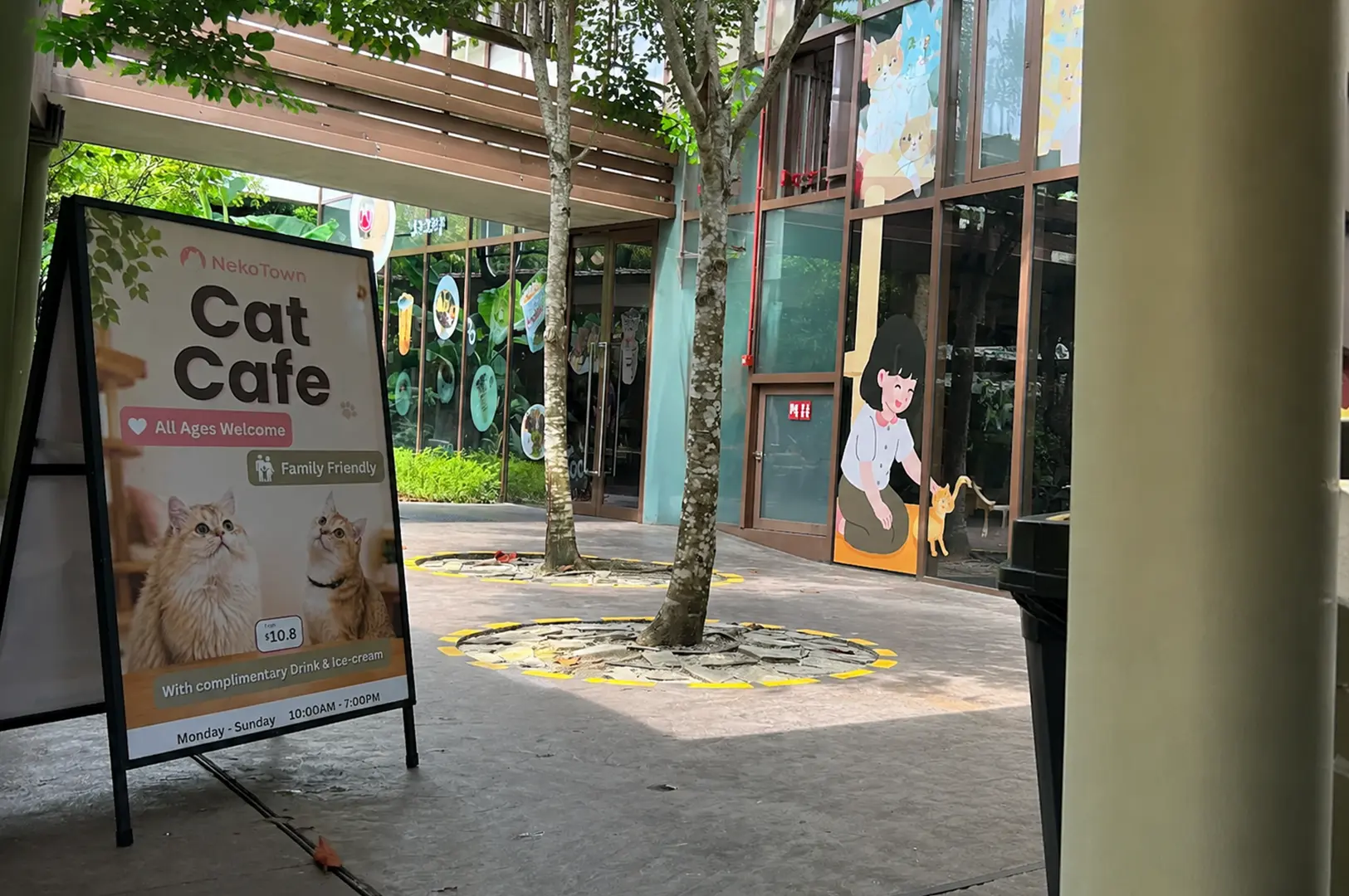 Outdoor view of NekoTown Cat Cafe with entrance sign and surrounding trees.