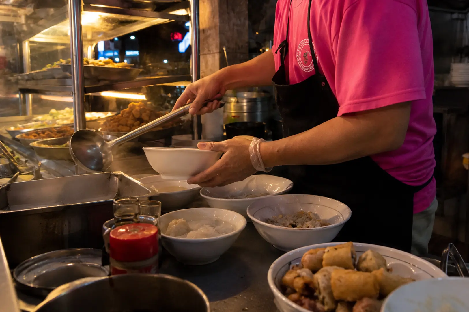 Staff serving hot soup at the dim sum counter with freshly prepared dishes on display.