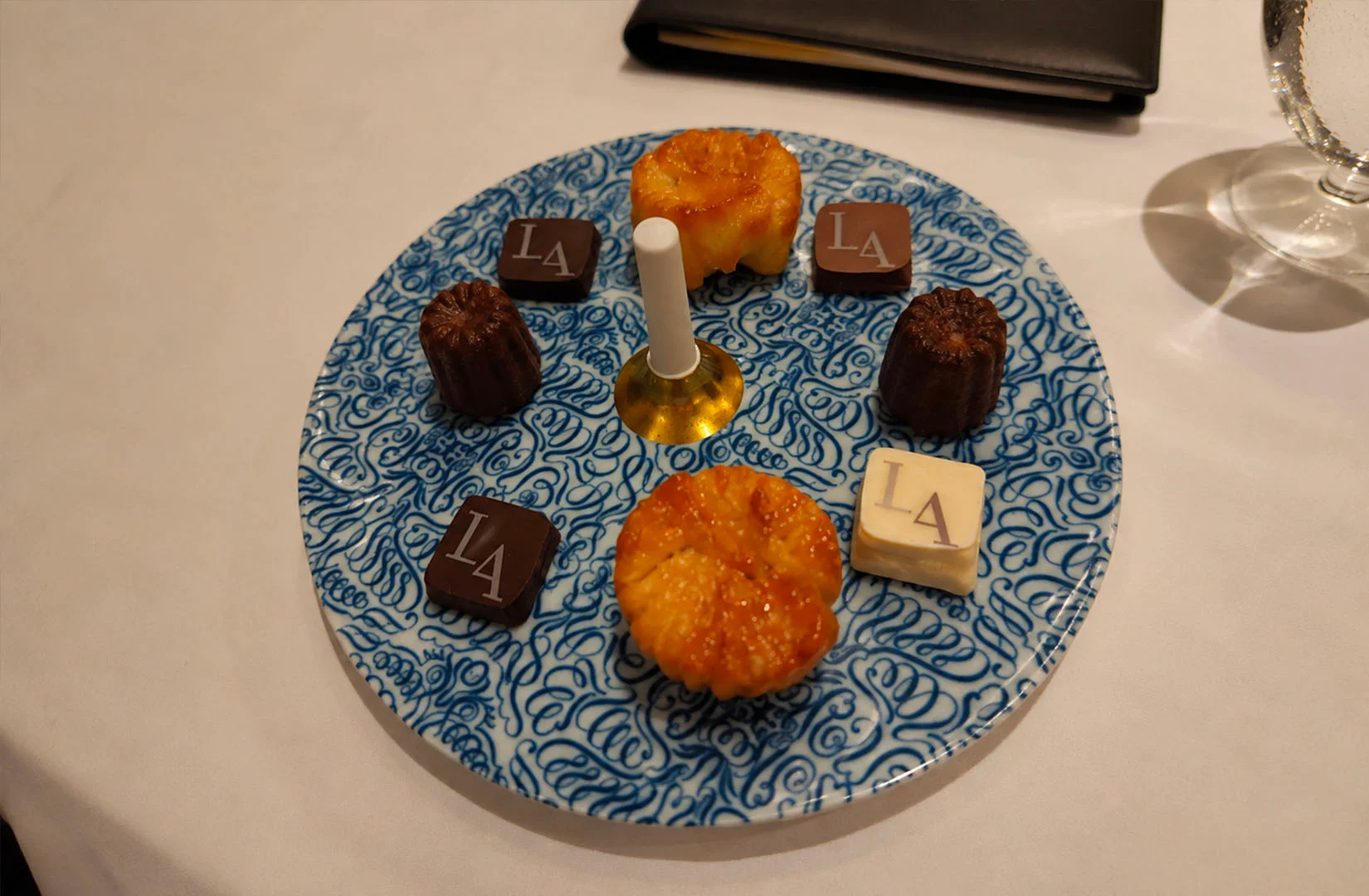 Selection of petit fours and chocolates beautifully presented on a decorative dessert plate.