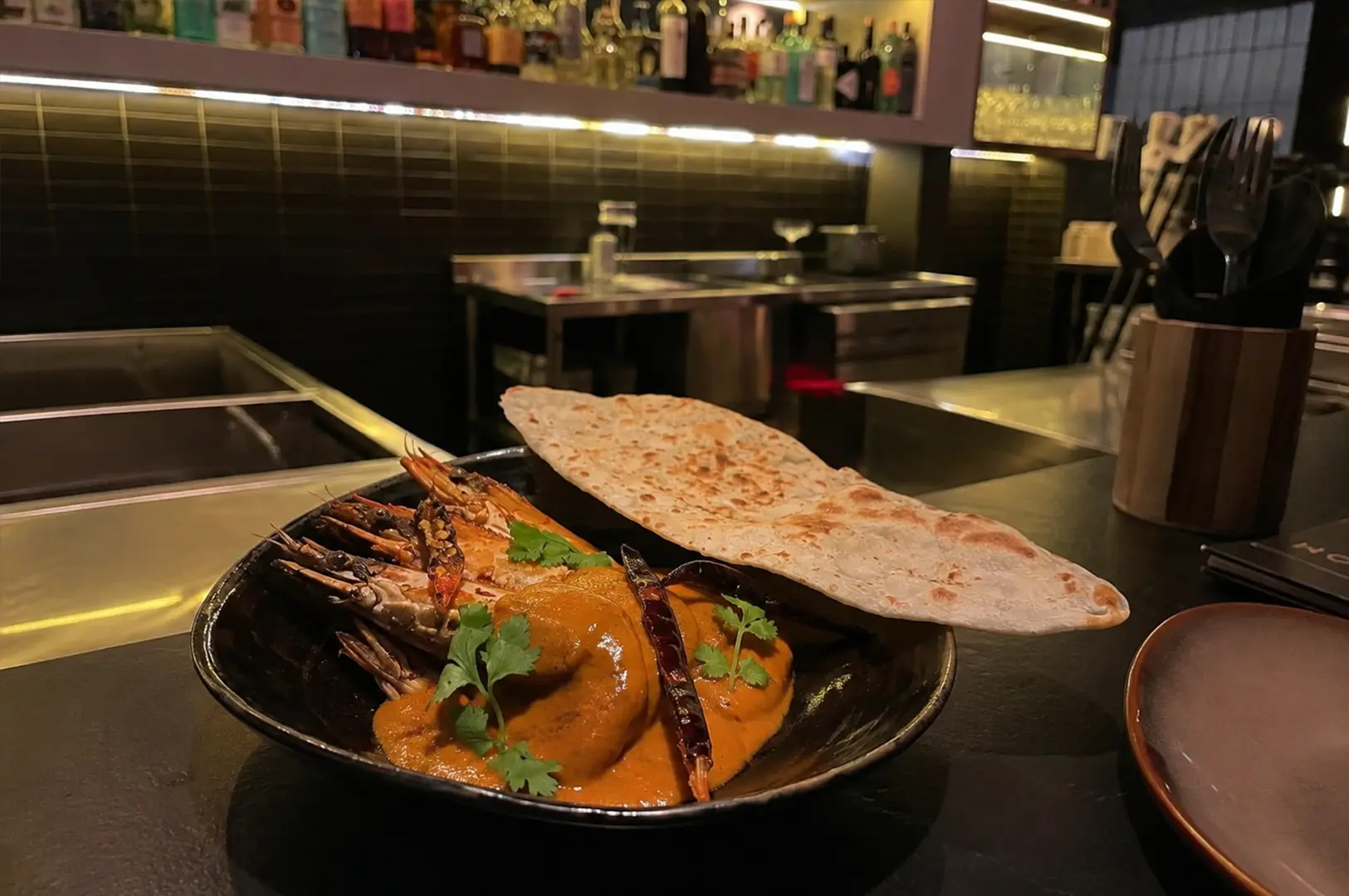 Tamarind Curry Prawns served with crispy papadum and fresh coriander at the bar.