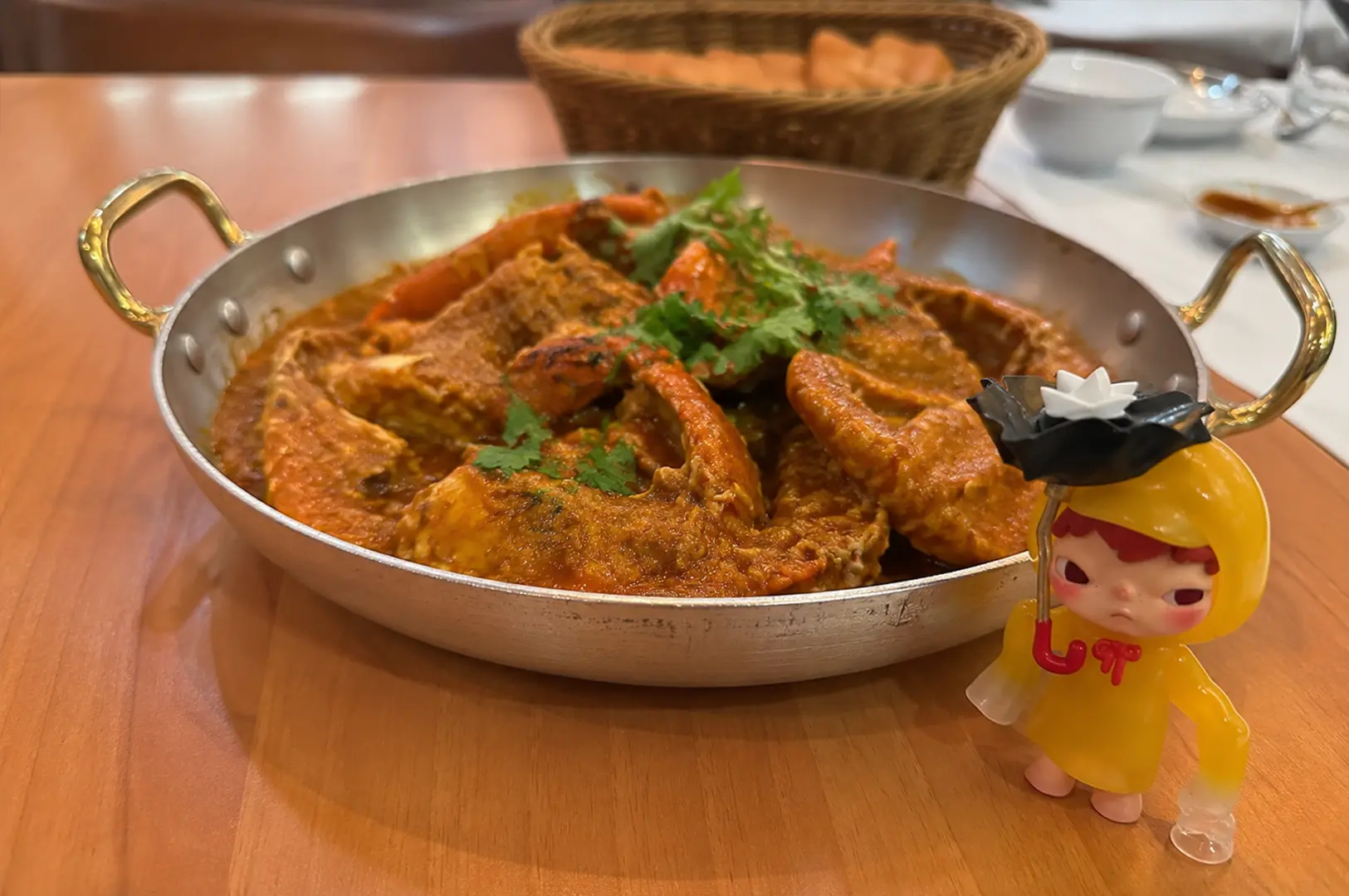 Singapore chilli crab served in a rich, spicy red sauce and garnished with coriander in a large metal pan.