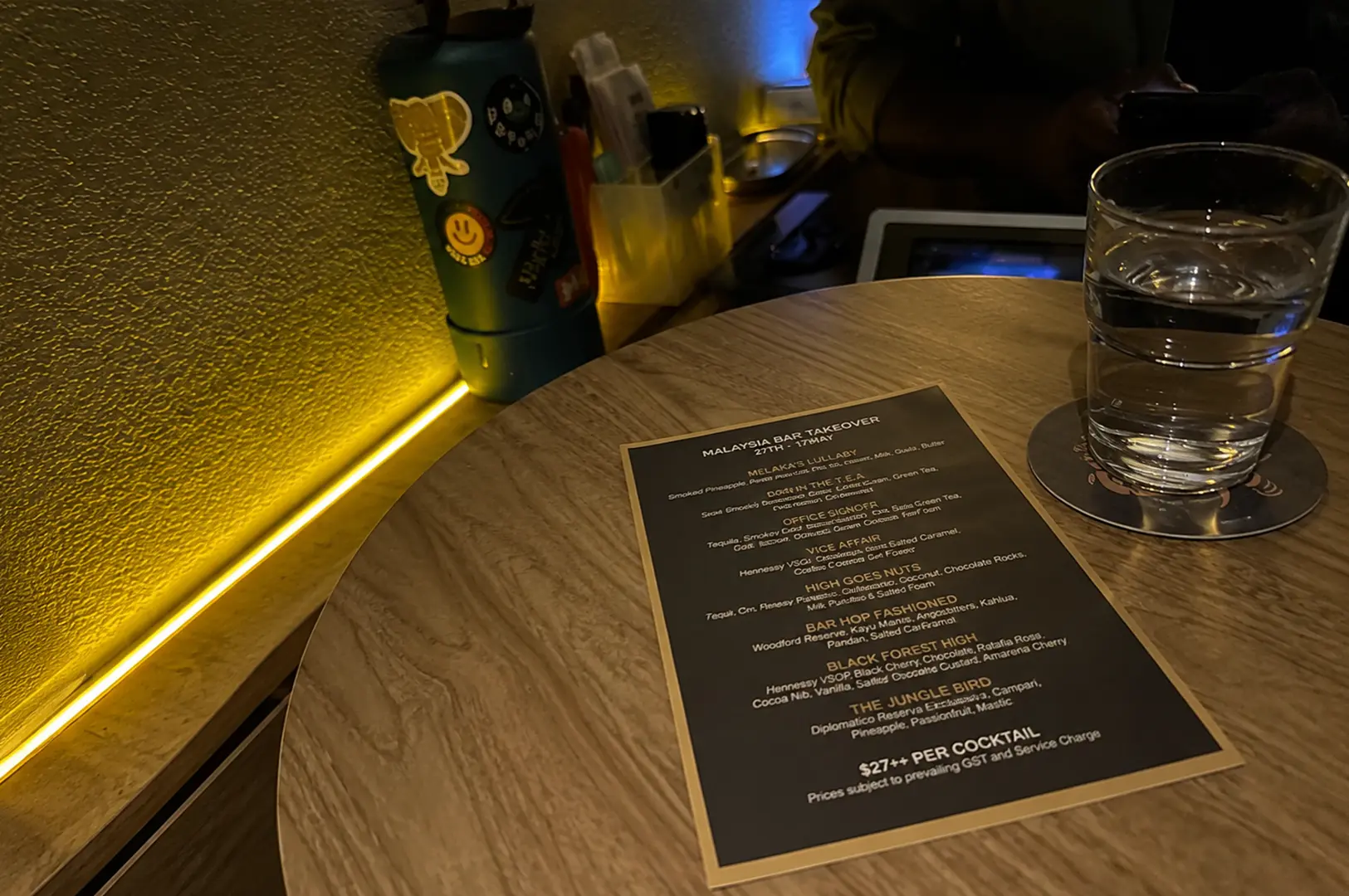 Cocktail menu displayed on a table with a glass of water inside The Elephant Room.
