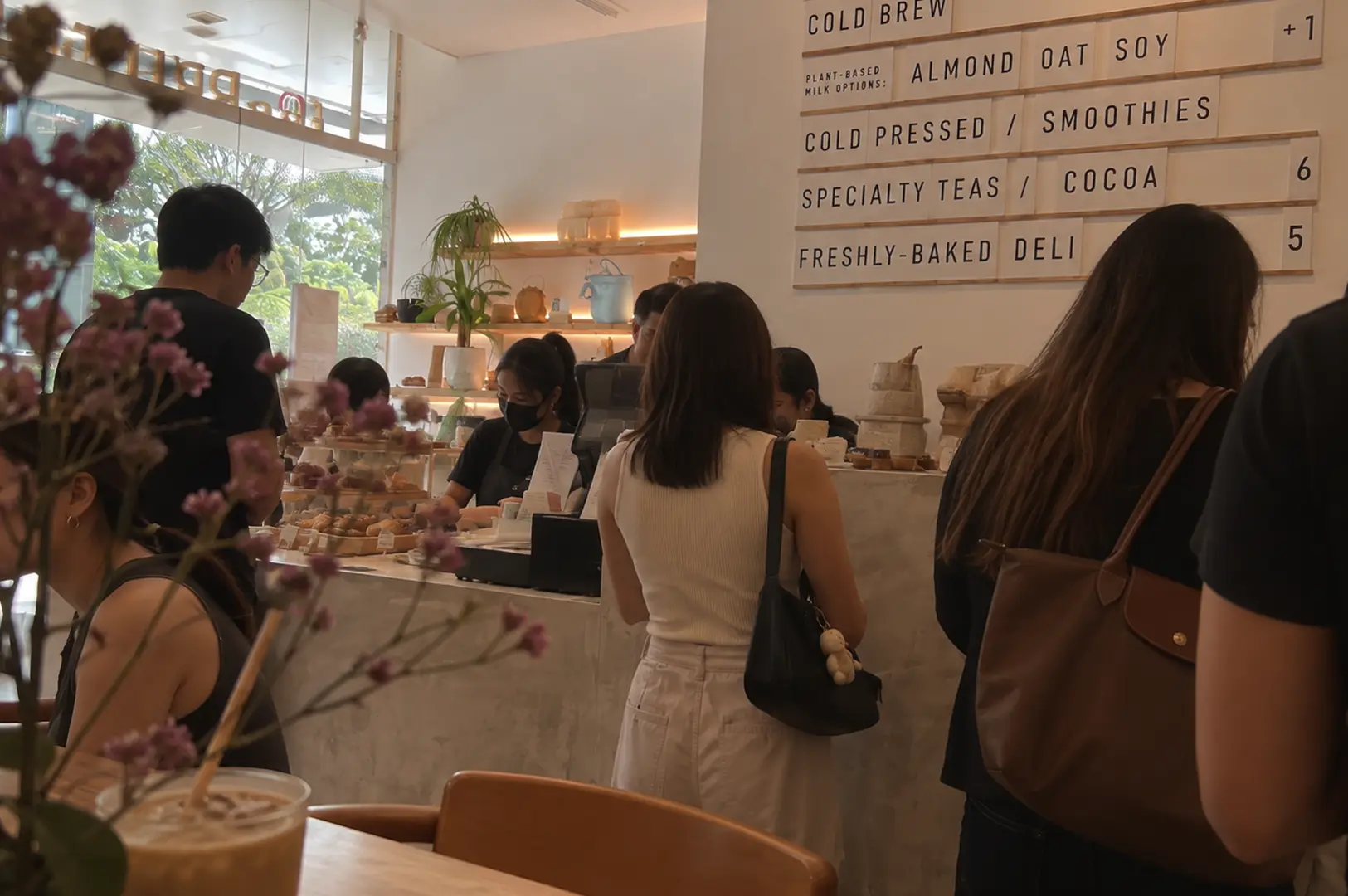 Busy café counter with several customers ordering drinks and pastries.