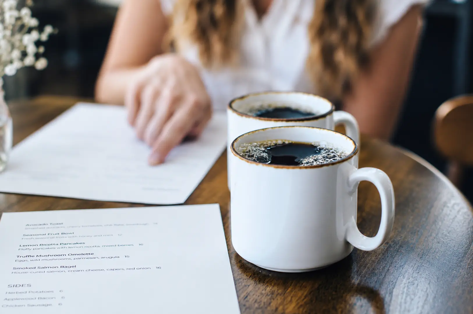 Two cups of black coffee on a café table beside a detailed menu.