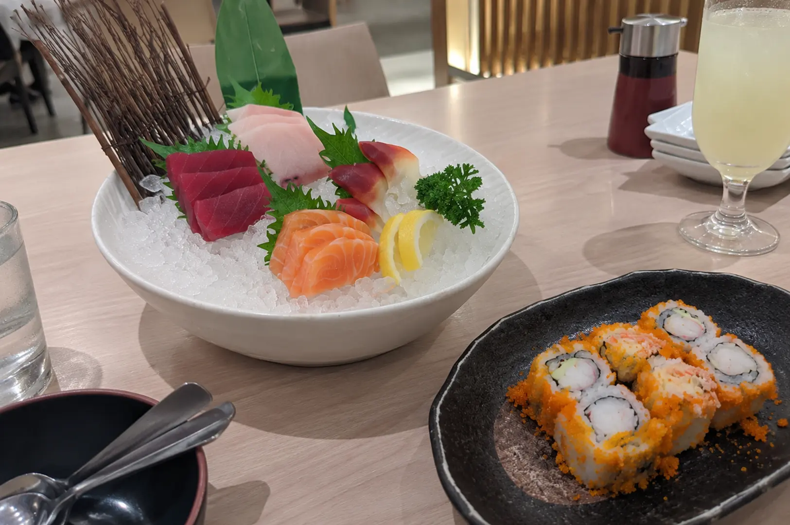 Fresh sashimi platter with salmon, tuna, white fish, and sushi rolls served on ice.