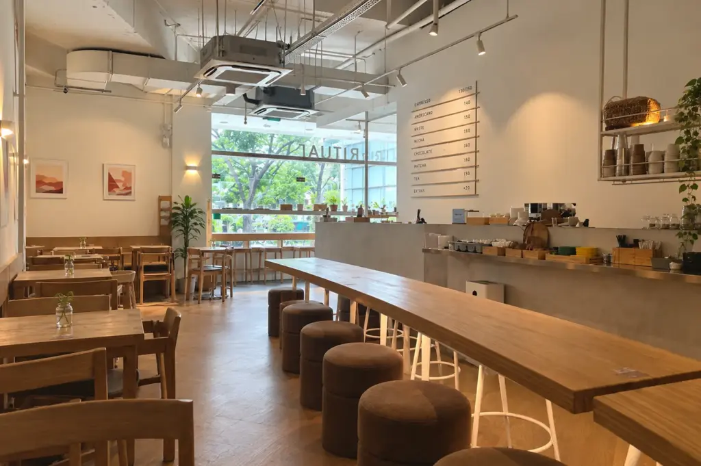 Quiet café interior with empty tables and a long wooden counter.