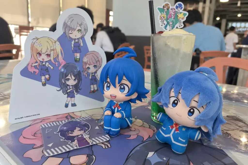 Kaito anime figures and plush displayed with a themed drink and character stand at an anime café.