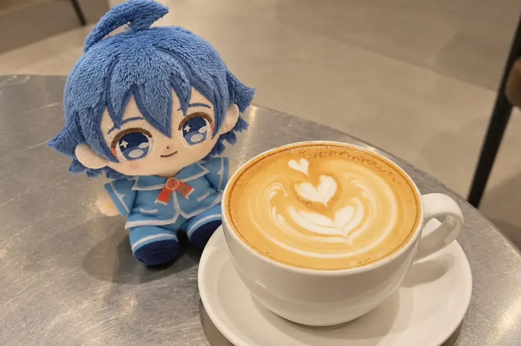 A blue plush toy sitting beside a heart-shaped latte on a café table.