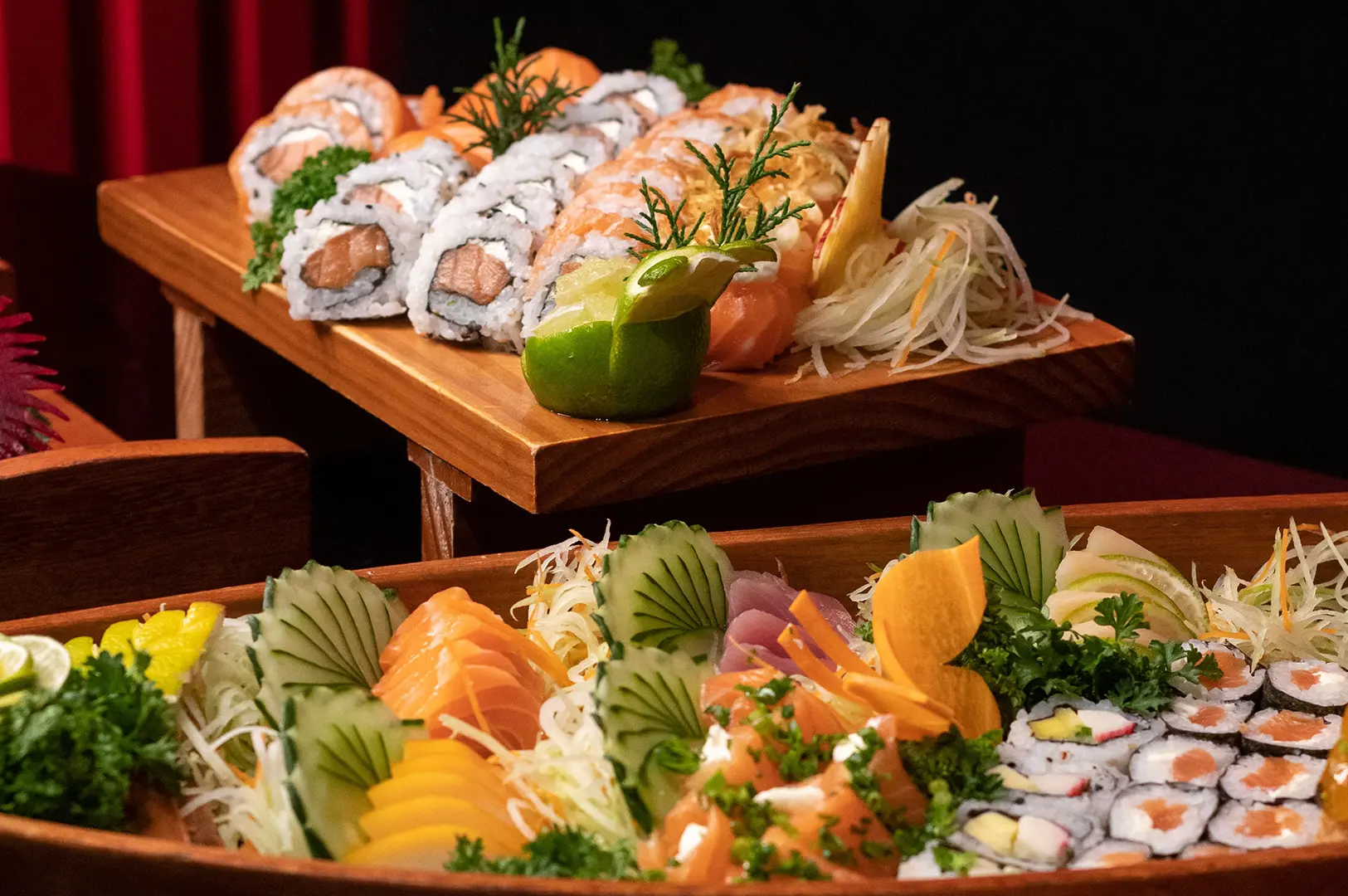 Assorted sushi rolls and sashimi beautifully arranged on wooden serving trays.