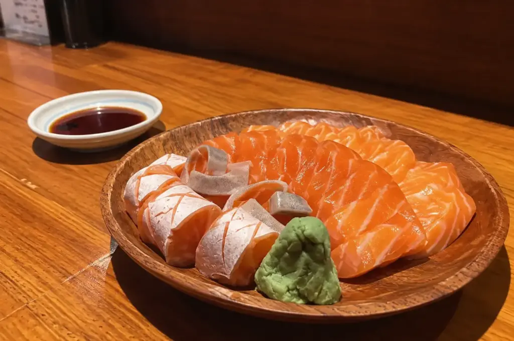 Salmon sashimi slices served with wasabi and soy sauce