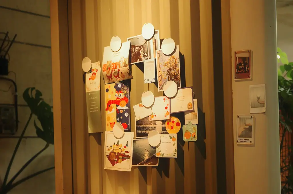 A wall display filled with colorful postcards, illustrations, and personal memorabilia, creating a distinctive café moodboard with its own personality