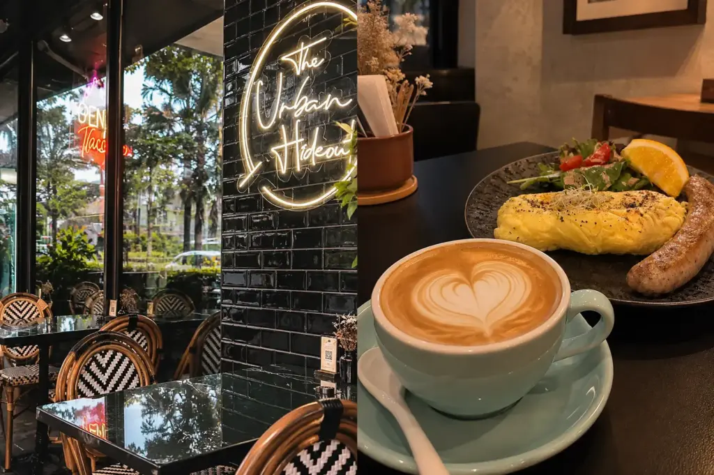 The Urban Hideout with a cozy black-tiled interior, woven chairs, outdoor views, and a latte with breakfast.