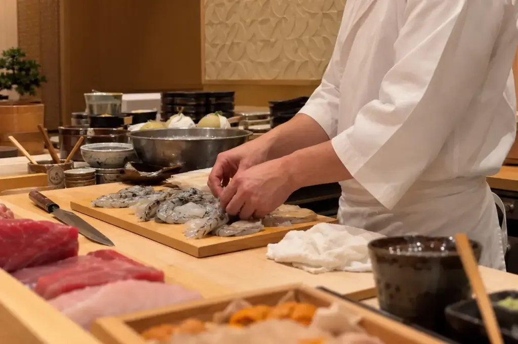 Omakase chef preparing fresh seafood behind a traditional Japanese sushi counter