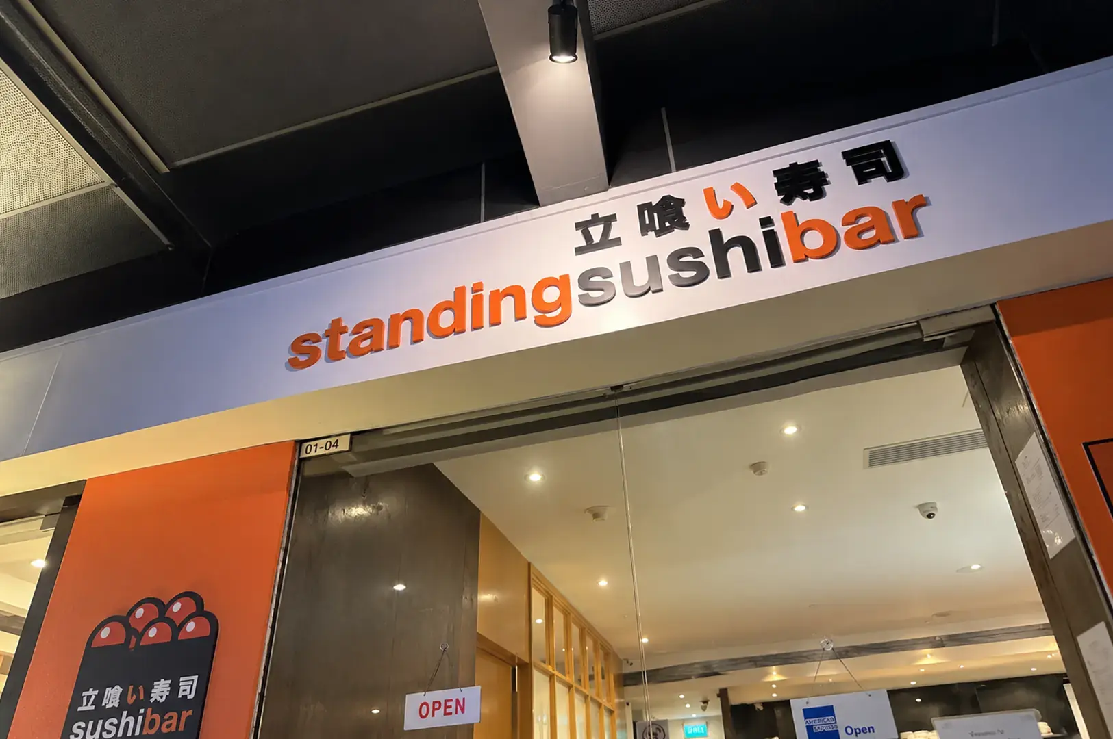 Standing Sushi Bar restaurant entrance with orange and black signage
