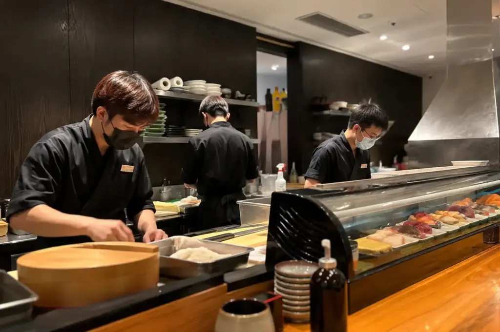 Sushi chefs preparing fresh dishes behind the restaurant counter