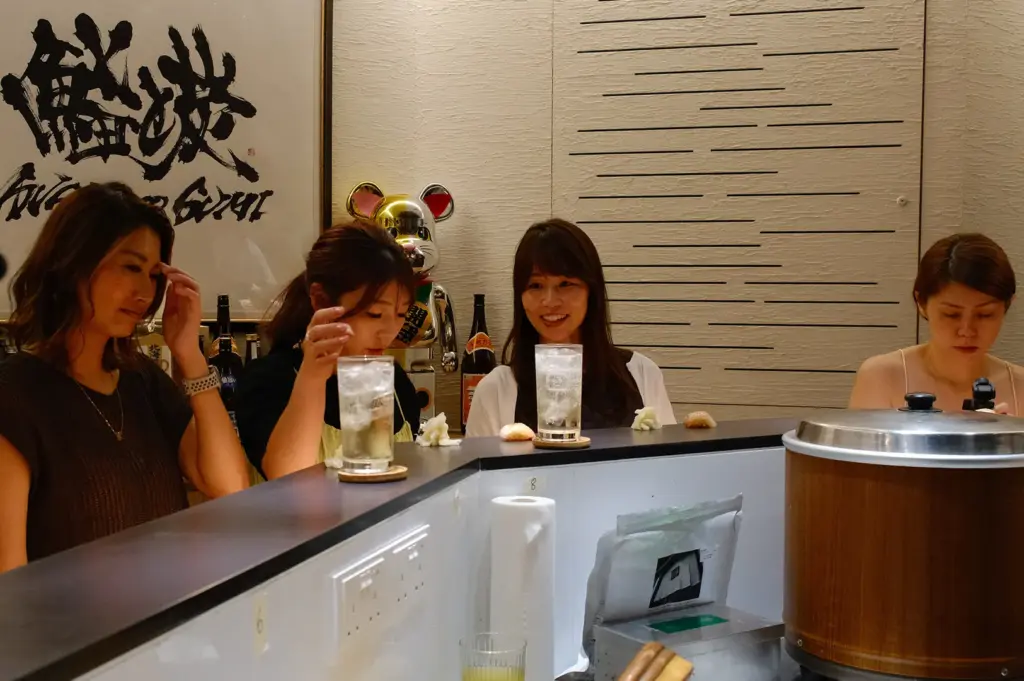 Diners enjoying sushi while standing at the counter, capturing Sushi To Sumi’s casual tachigui-style dining experience.