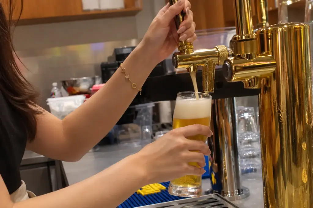 A freshly poured glass of golden beer served from a brass tap at Soup Curry by Kisetsu.