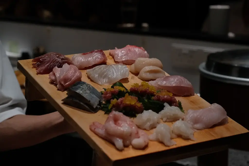A wooden board filled with different cuts of fresh fish and sushi, showcasing the variety of seafood at Sushi To Sumi.