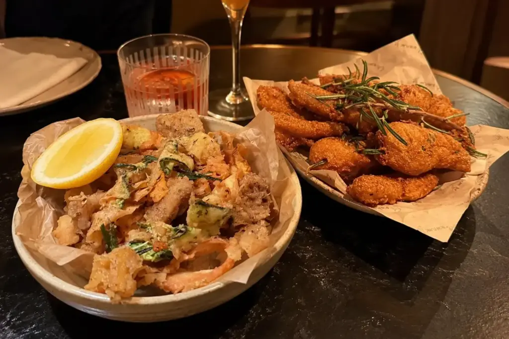 Golden crispy fries and fried appetizers served in ceramic bowls with a lemon wedge and fresh rosemary.