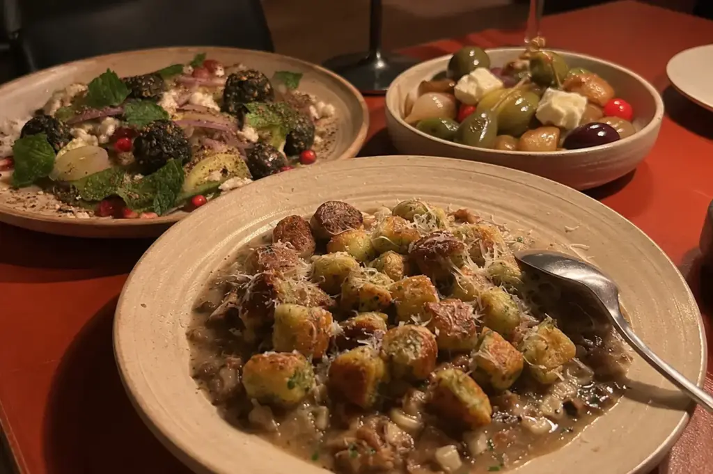Parisian gnocchi served with mushroom sauce and Parmesan, alongside a fresh salad and a bowl of olives.