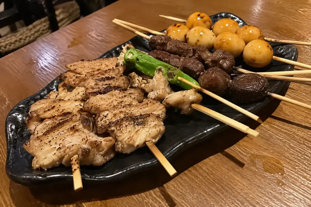 Yakimono set featuring assorted grilled chicken and meat skewers, asparagus, mushrooms, and glazed quail eggs.
